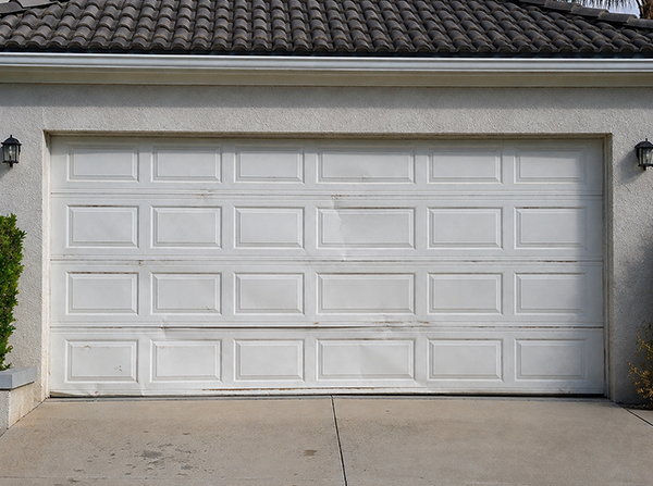 Residential garage door showing dents and wear before repair service